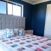Bedroom painted dark blue showing snail quilt on bed and bedside table.