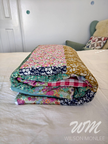 All folded up on the bed. You can see both the folds of the quilt and the top of the folded quilt. 