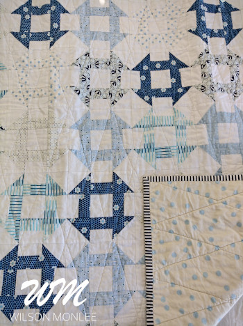 Full frame of churn dash quilt showing backing, binding and quilting